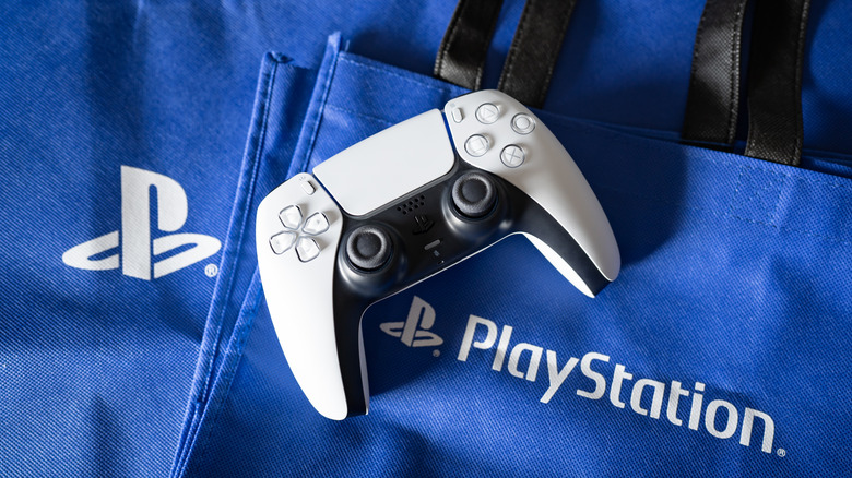 A PlayStation DualSense controller laid atop a PlayStation-branded tote bag
