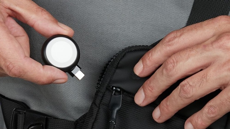 Hand holding Belkin BoostCharge Portable USB-C Apple Watch Charger and putting it in bag
