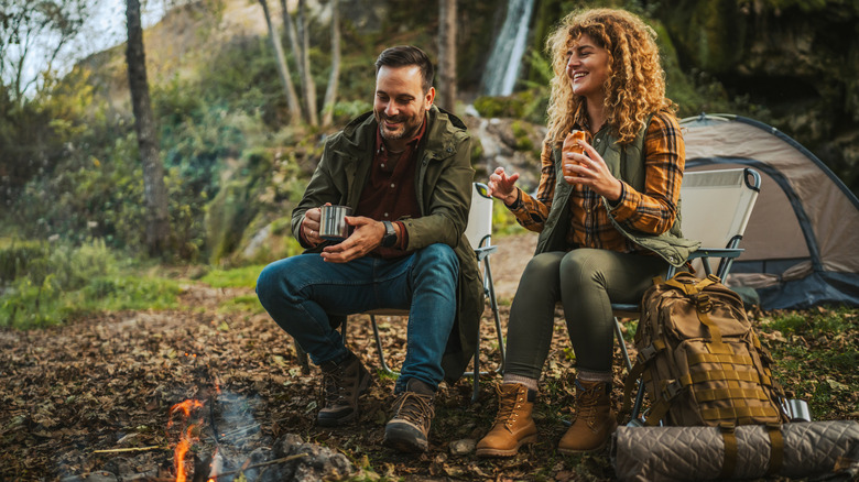 A man and a woman sitting near a  fire pit