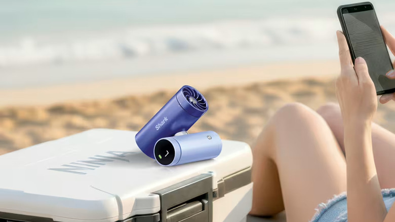 Sharp ChillPill sitting on a cooler, blowing cool air on a person at the beach