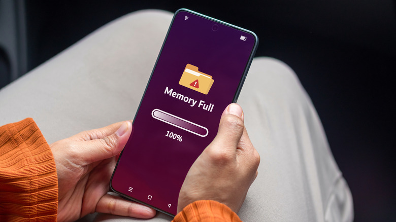 A person holding a smartphone with storage full notification on the phone screen