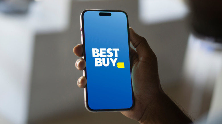 A person holding a smartphone with a Best Buy logo.