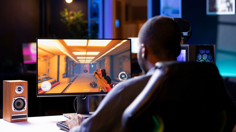 Person playing a first-person shooter game on a desktop PC setup.