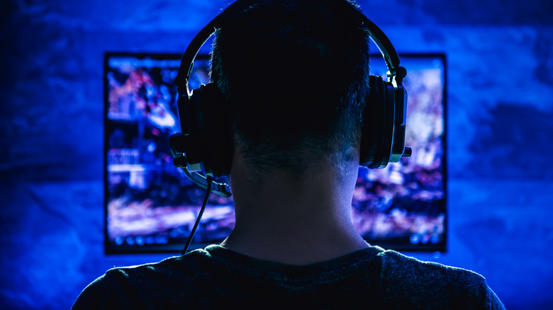 Person wearing headphones using a computer in a dark setup.