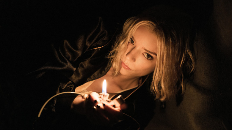 Lucky Armstrong is illuminated by a lighter as she tries to light the fuse of an explosive in a dark, cramped space.