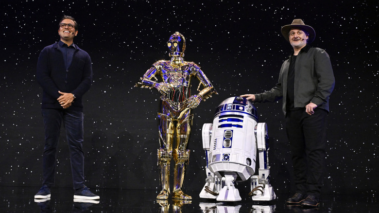 Dave Filoni on stage with C3PO and R2D2 at the Star Wars Celebration event.