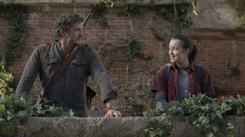 Joel and Ellie talking beside ivy-covered wall in The Last of Us (2023)