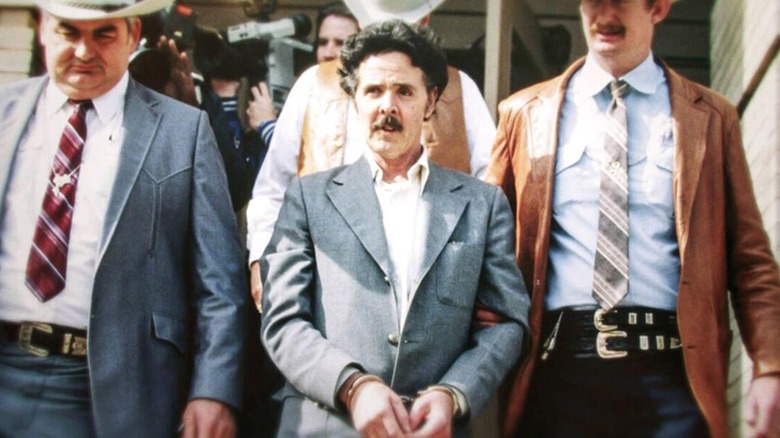 Henry Lee Lucas in handcuffs with police officers escorting him