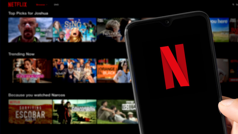 Netflix logo on a smartphone in front of a smart TV