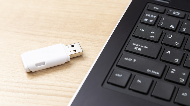 A USB-A flash drive next to a laptop.