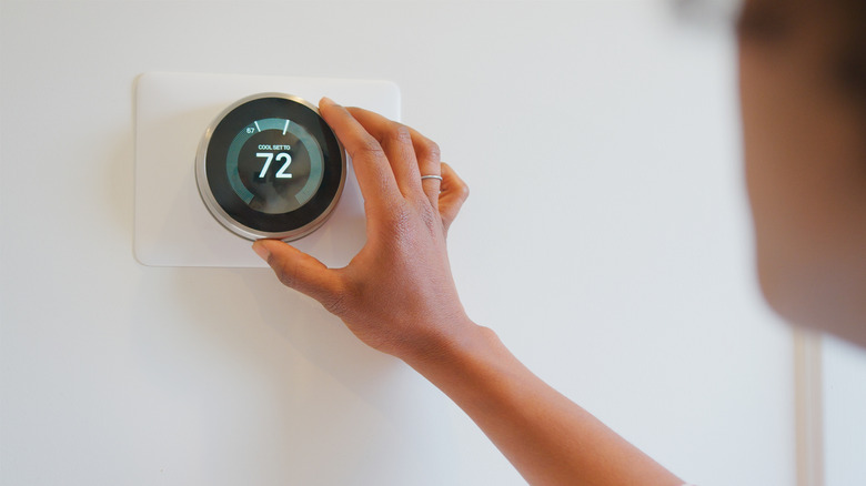 Close-Up of woman setting digital smart heating thermostat at home