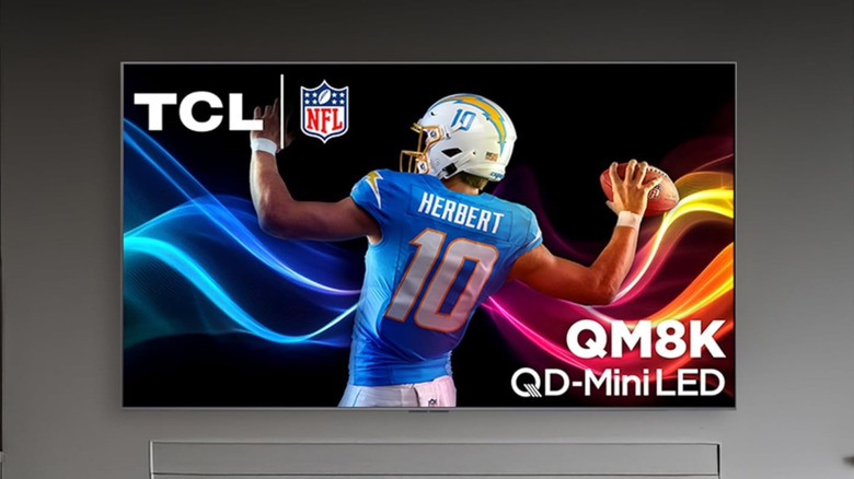 The TCL QM8K wall-mounted above a fireplace.