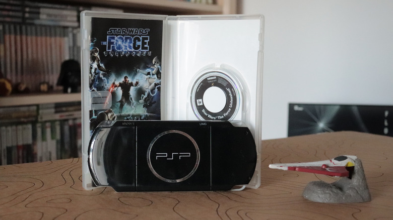 A PSP in front of a copy of Star Wars: The Force Unleashed.
