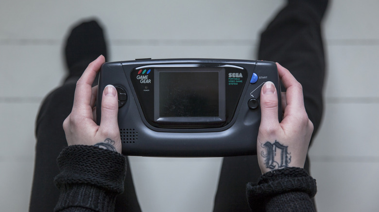 Person holding Sega Game Gear while looking at floor