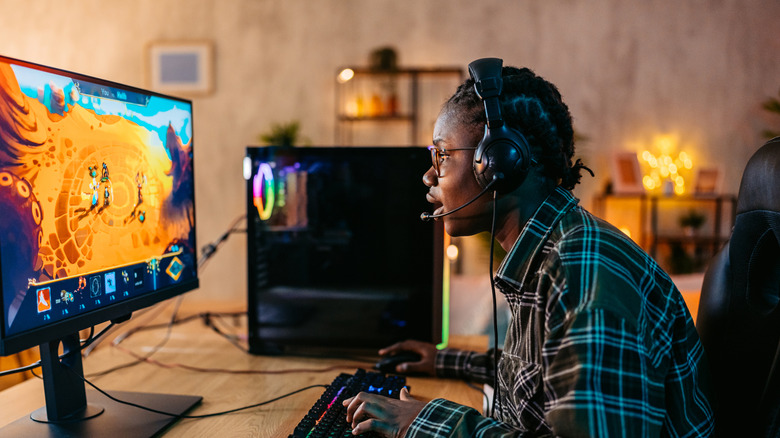 Person playing a game on their PC and wearing a headphone