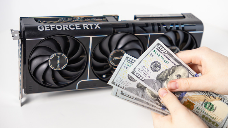 Person holding hundred-dollar bills in front of GeForce RTX card