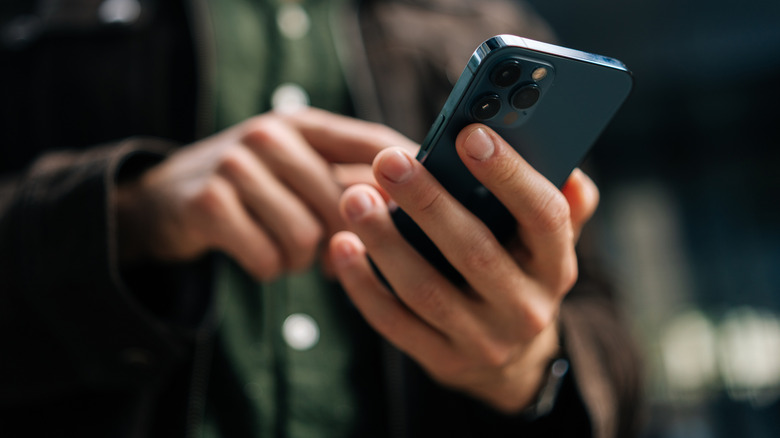 A person holding an iPhone and tapping the screen.