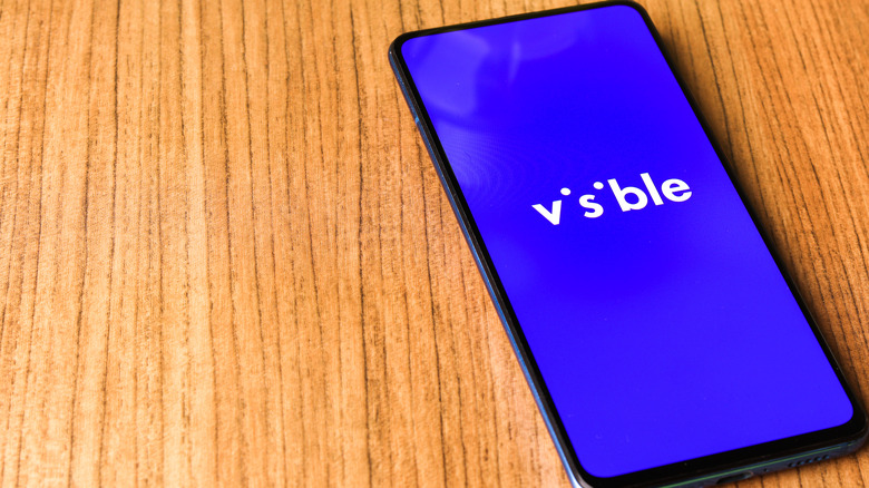 The Visible (for Verizon) app running on a smartphone resting on a wooden surface.