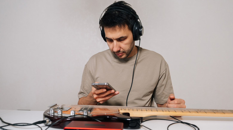 A person wearing headphones and looking at their smartphone