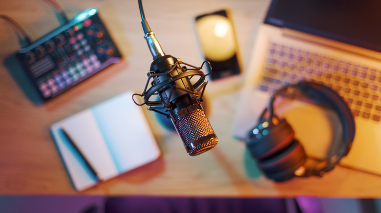A top-down shot of a desk with a microphone and podcast accessories around it.