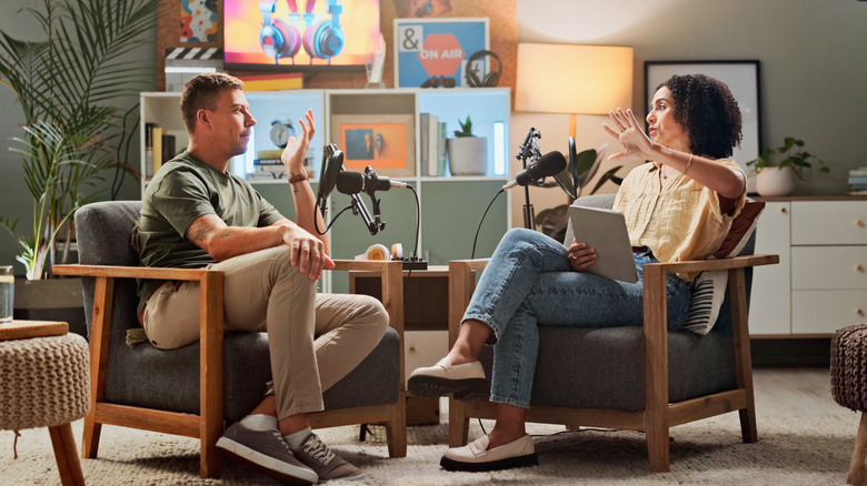 Two people sitting in chairs recording a conversation podcast