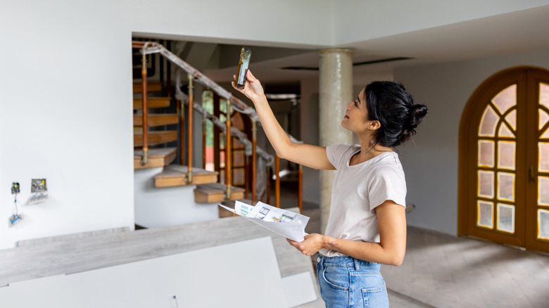 A person holding a phone and home improvement documents