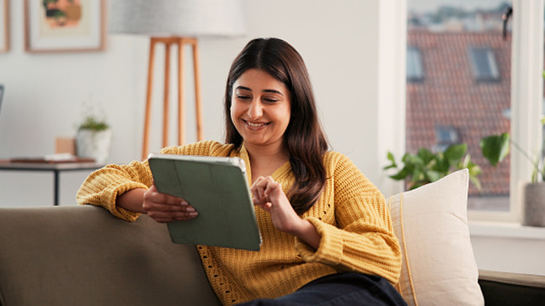A woman smiling while looking at something on a tablet