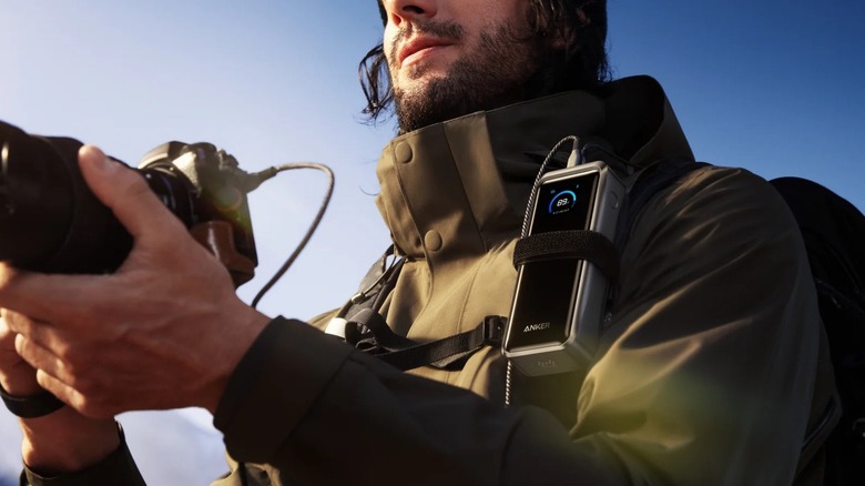 A man outdoors with an Anker power bank attached to his jacket