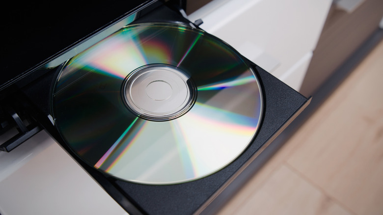 A close-up of a Blu-ray or DVD disc being placed in a player disc drive