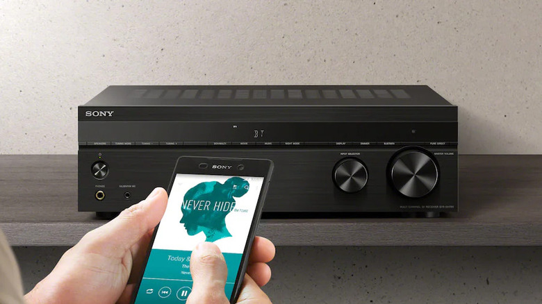 A person using a smartphone to stream music to a Sony STR-DH790 AV receiver.
