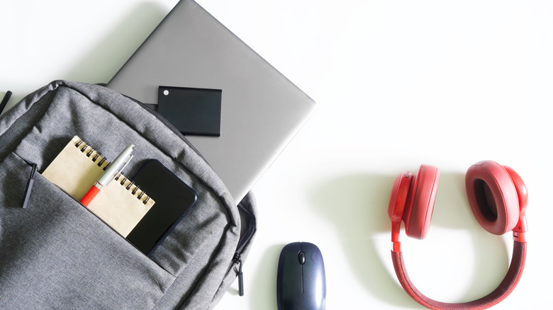 A backpack with a laptop, power back, notebook, pen and phone in the pocket.