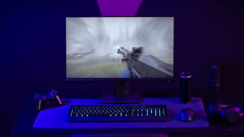 Gaming monitor showing a first-person shooter on a purple-lit desk setup.