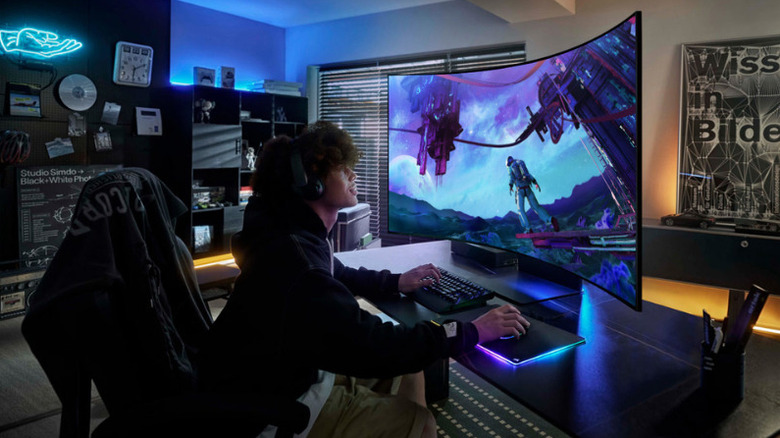 Gamer using a Samsung Odyssey Ark 2nd Gen curved monitor in a neon-lit desk setup.