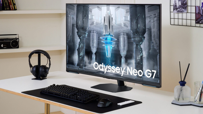 Samsung Odyssey Neo G7 monitor showing a futuristic game scene on a clean desk.