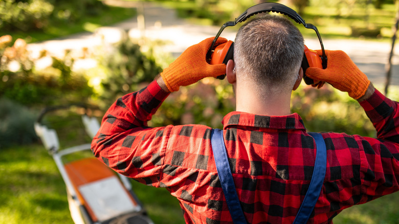 A worker putting on hearing protection earmuffs.