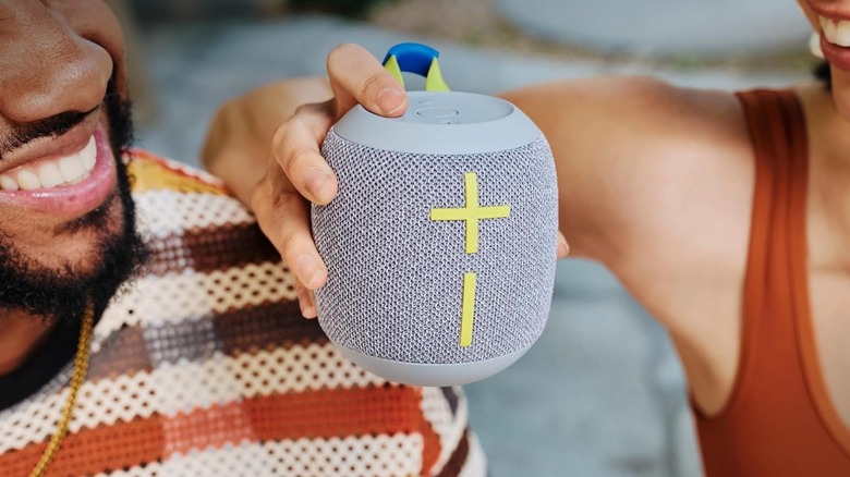 A couple holding the UE Wonderboom 4 against a blurred background.