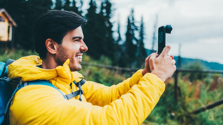 Person shooting a photo using a phone with a camera lens attached