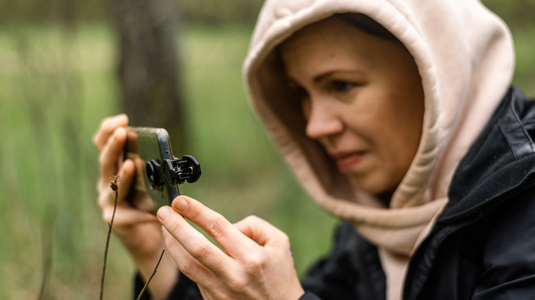 Lady holding a phone with a camera lens attached