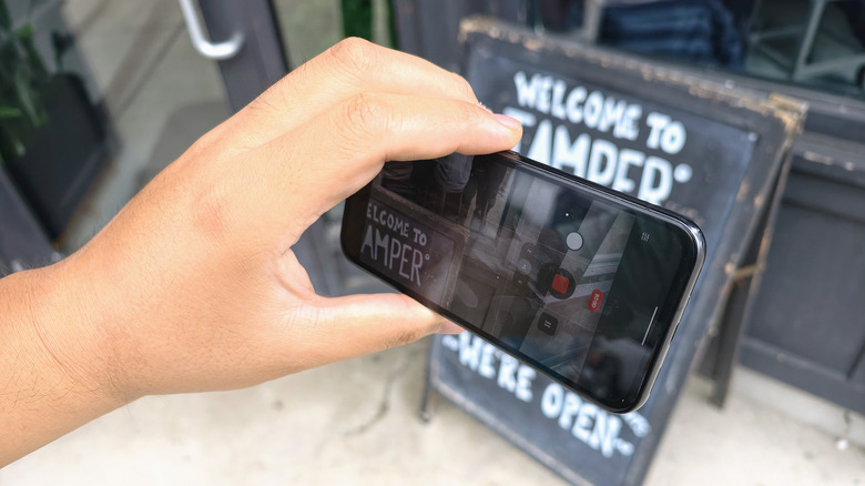 A man using a Pixel 8a to shoot video outside of a cafe.
