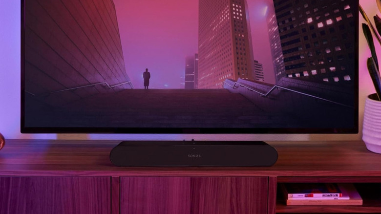 The Sonos Ray set up on top of a TV stand below a wall-mounted TV.