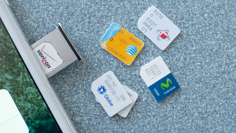 SIM cards from multiple wireless carriers placed beside a smartphone.