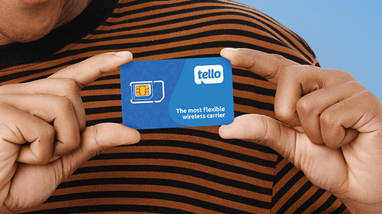 Person holding a blue Tello SIM card against a striped shirt.