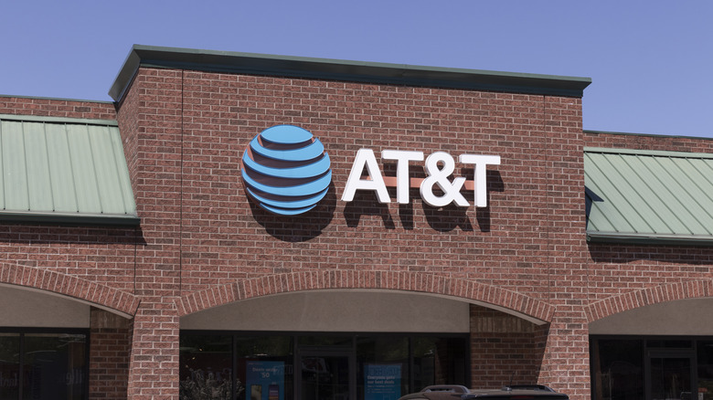 AT&T logo displayed on a brick storefront under a clear blue sky.