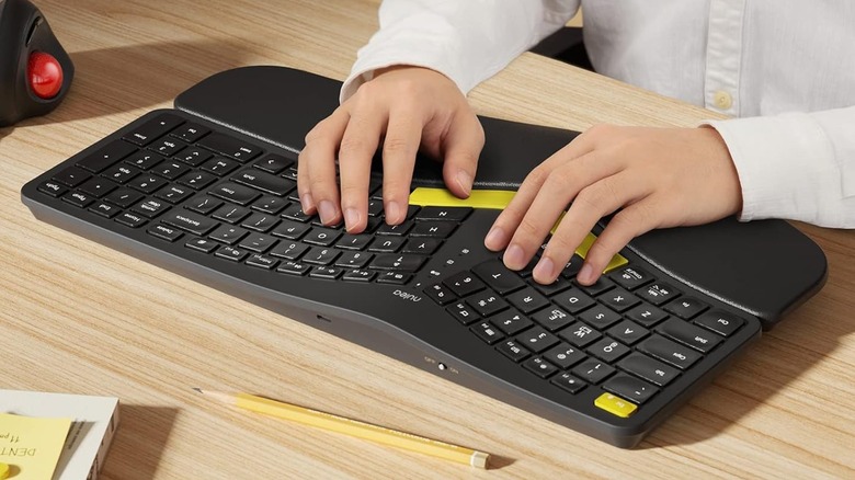 A user in a white shirt has both hands on a Nulea RT05 ergonomic keyboard
