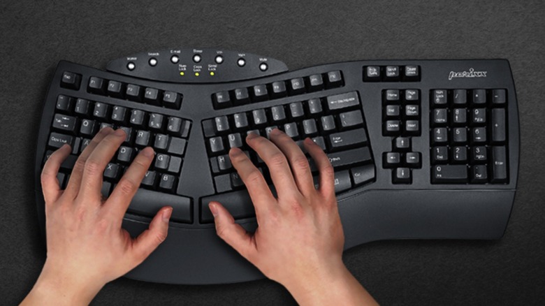 A closeup of two human hands on a black Perixx Periboard 612B ergonomic keyboard, the keyboard sits against a black surface