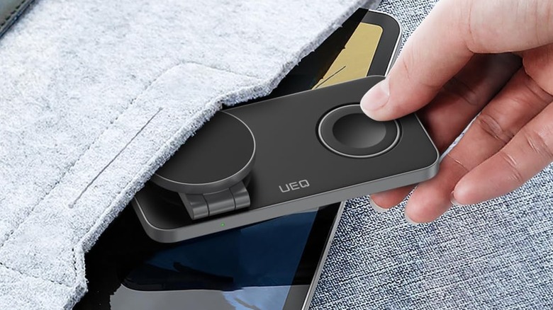 A person placing a UEQ folding charger in a bag.