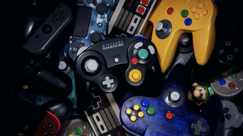 A Nintendo Gamecube controller sitting atop a pile of other game controllers