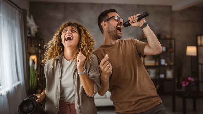 A couple singing with a microphone and karaoke machine in hand