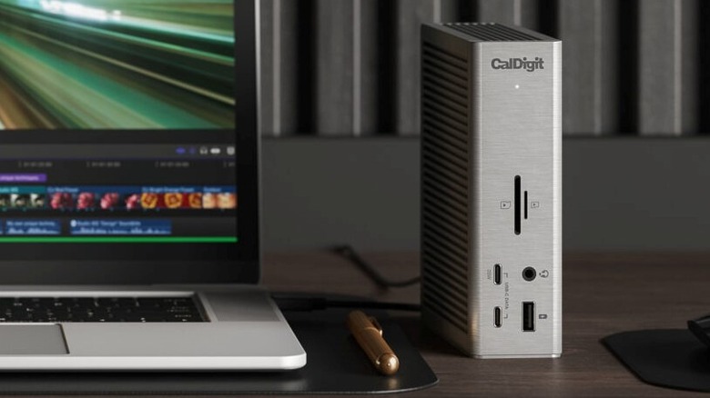 A CalDigit TS4 Dock sitting on a desk next to a MacBook