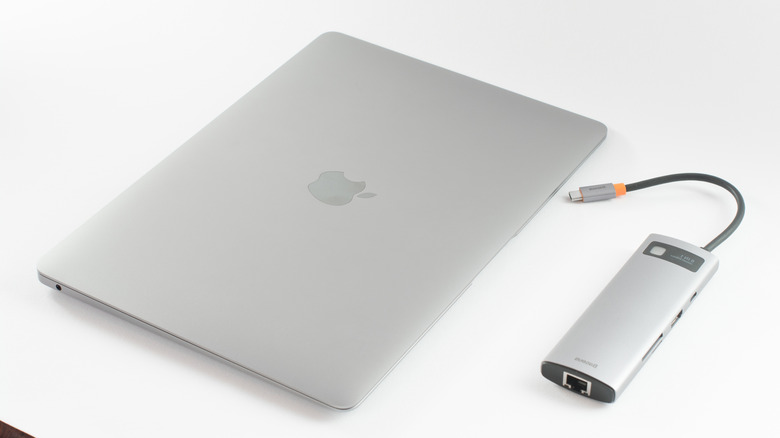 A MacBook with a USB hub next to it is pictured.